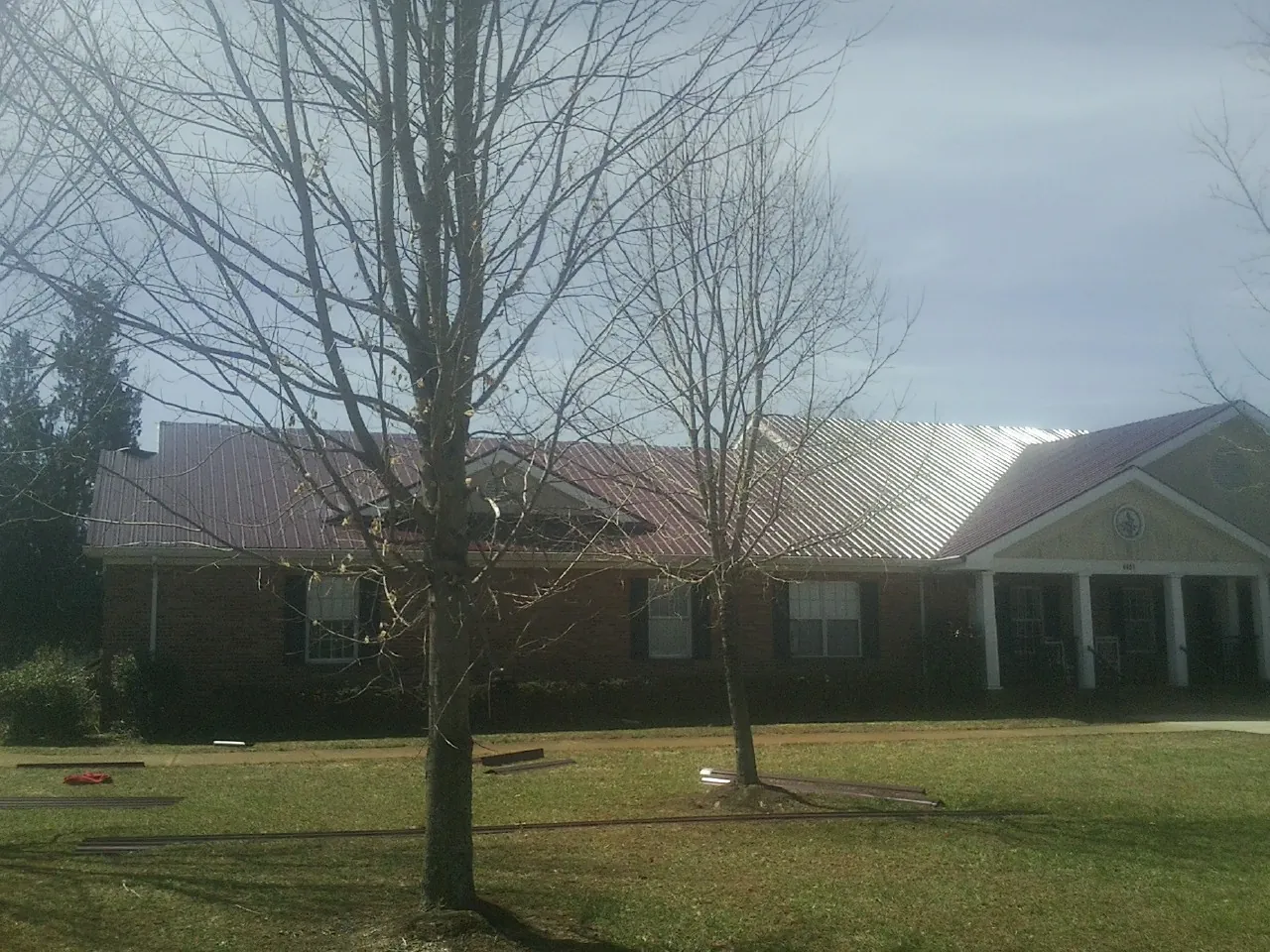 Red metal roof on a brick building seen from the front lawn in Sterling